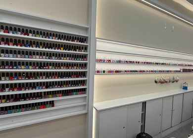 Palette Nails Studio in New York displays an array of colorful nail polishes on elegant shelves.