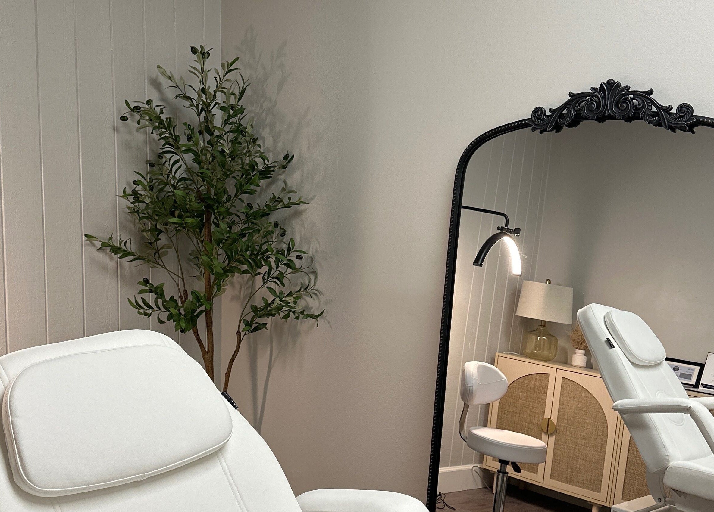 Relaxing treatment room at All Things Skyn, Glendale, California, US with a plush chair and ornate mirror.