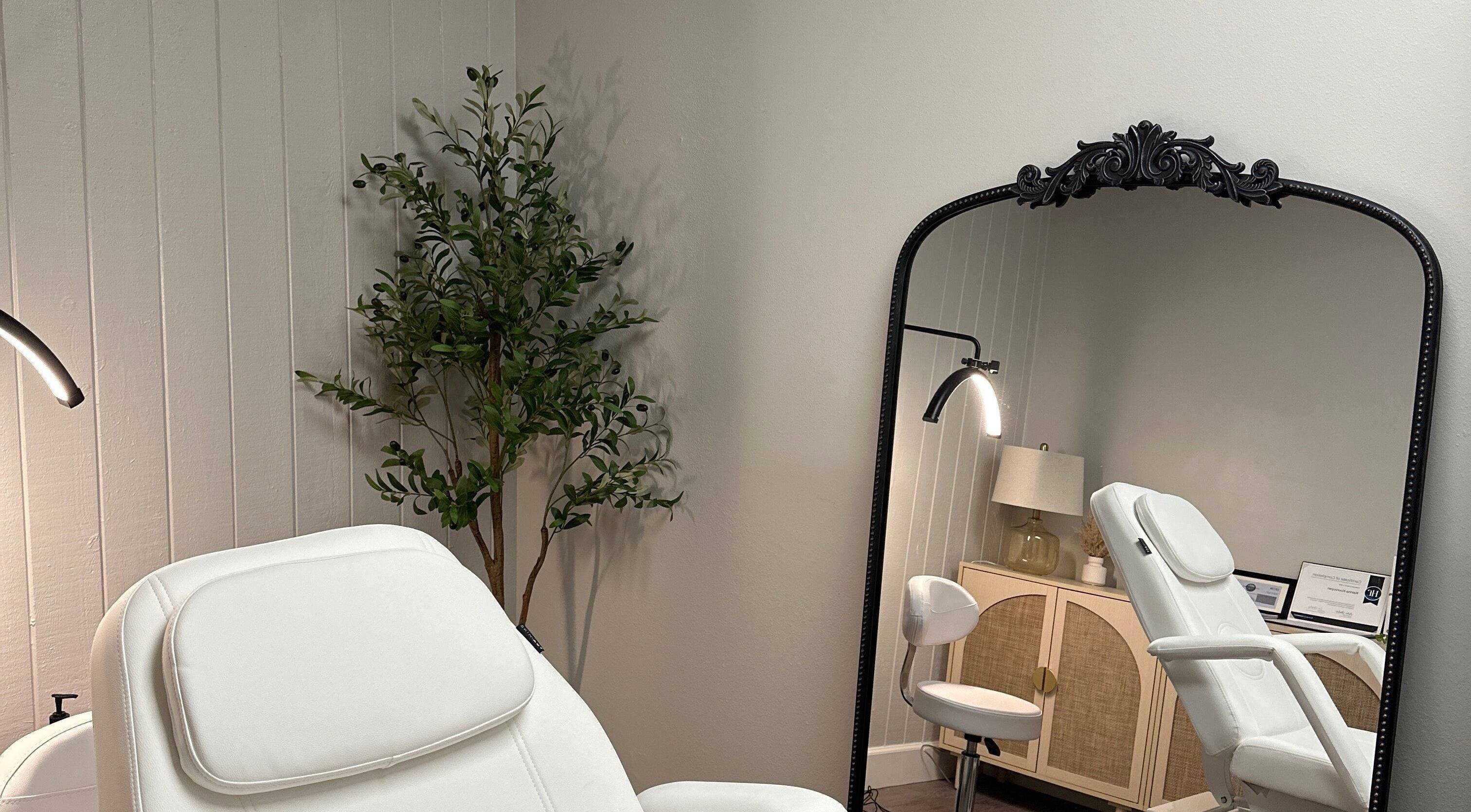 Relaxing treatment room at All Things Skyn, Glendale, California, US with a plush chair and ornate mirror.