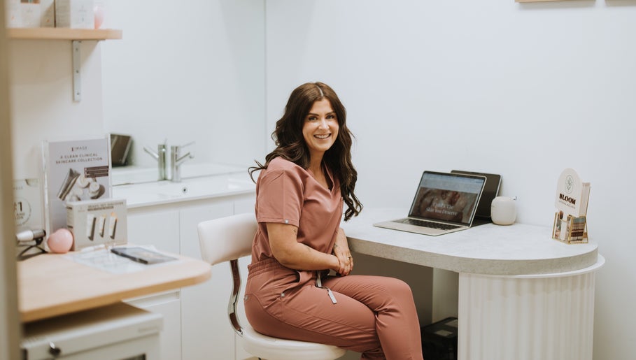 A smiling wellness specialist at Bloom Integral Wellness in Melbourne, Victoria, AU, sitting in a consultation room.