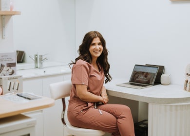 A smiling wellness specialist at Bloom Integral Wellness in Melbourne, Victoria, AU, sitting in a consultation room.