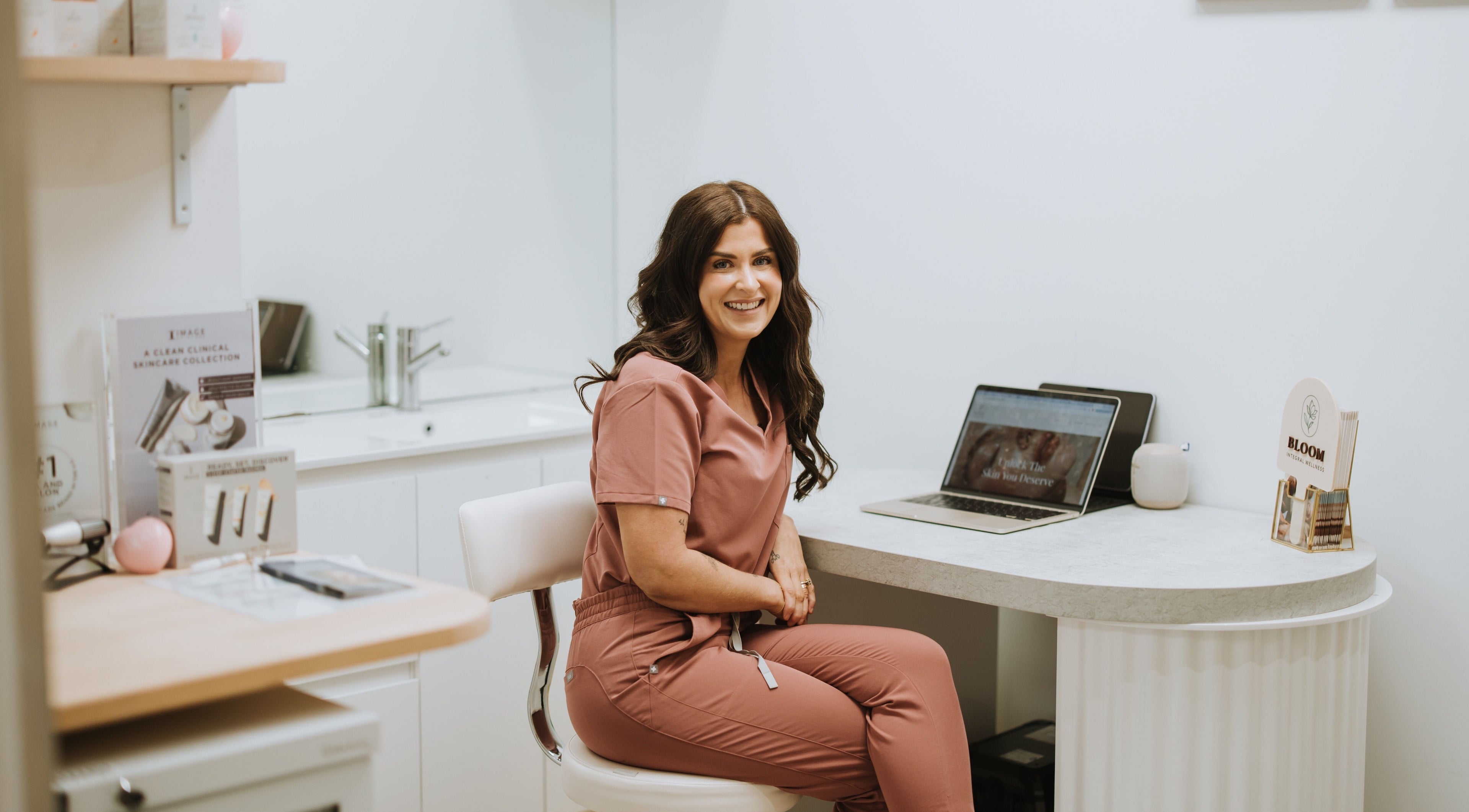 A smiling wellness specialist at Bloom Integral Wellness in Melbourne, Victoria, AU, sitting in a consultation room.