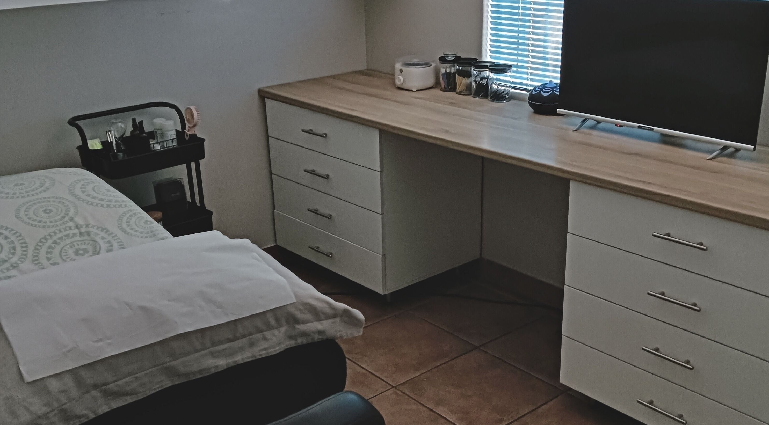 Relaxing spa room at L AND B in Cape Town, Western Cape, ZA, featuring a cozy bed and organized workspace.