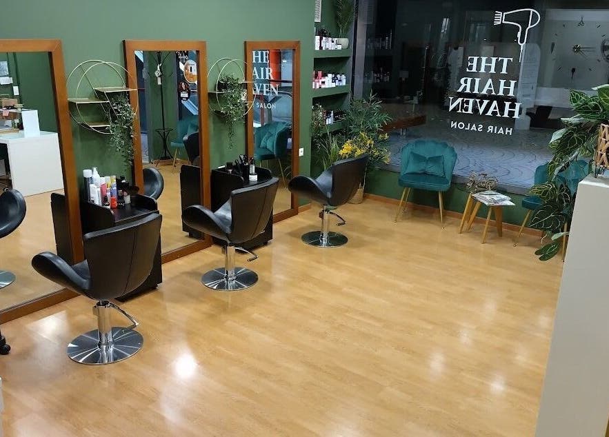 Το κομψό σαλόνι The Hair Haven στη Γλυφάδα, GR με καθίσματα και καθρέφτες.