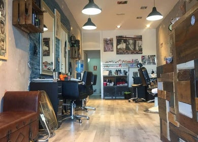 Interno del salone HairRock ad Arona, Canarias, ES con arredi rustici e sedie moderne.