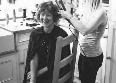Client enjoying hairstyling at SO Hair, Stafford, England, GB. A moment of laughter during a session.