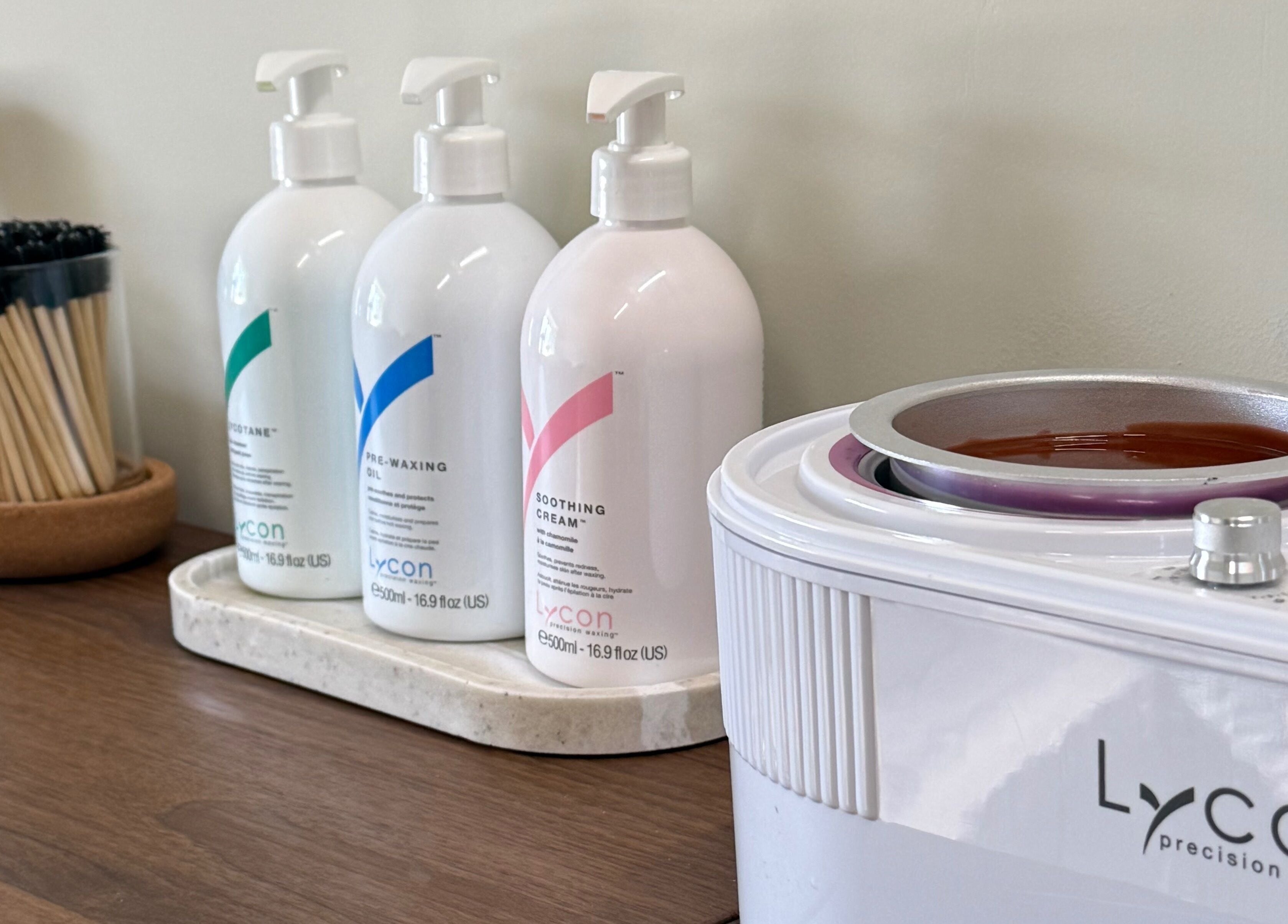 Lycon waxing supplies at Strp., Edinburgh, Scotland, GB. Bottles and wax heater on a wooden counter.