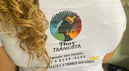 Detalhe da camiseta do Studio Thay Trancista, Rio De Janeiro, com cabelo loiro exuberante ao lado.