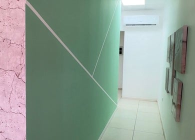 Modern hallway at Glorious Touch Day Spa, Oranjestad, AW, featuring abstract wall art and calming green tones.