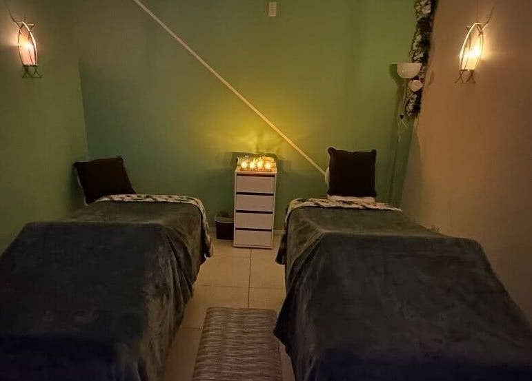 Relaxing massage room at Glorious Touch Day Spa in Oranjestad, AW, featuring dim lighting and cozy beds.