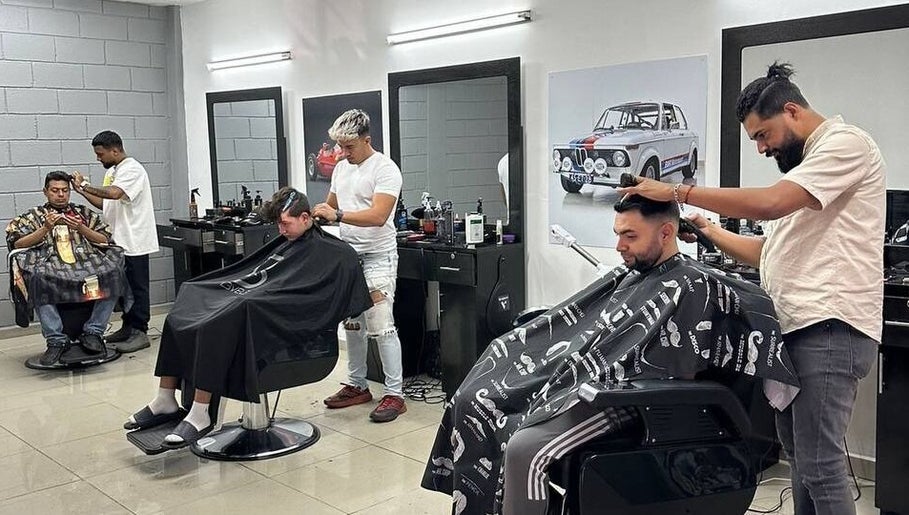Interior de Barbería Mónaco en Tegucigalpa, Departamento De Francisco Morazán, HN, mostrando barberos trabajando.