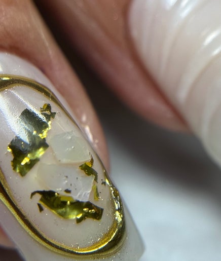 Uñas decoradas en Minou’s Studio, Ambato, Tungurahua, EC: elegancia en dorado sobre blanco.