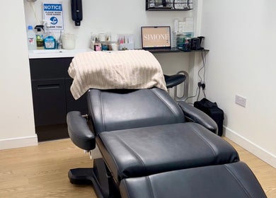 Relaxing treatment room at Simone Services, Edinburgh, Scotland, GB, featuring a plush black reclining chair.