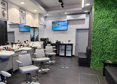 Modern interior of Db Barbers Tooting Bec, London, England, GB with sleek chairs and green accent wall.