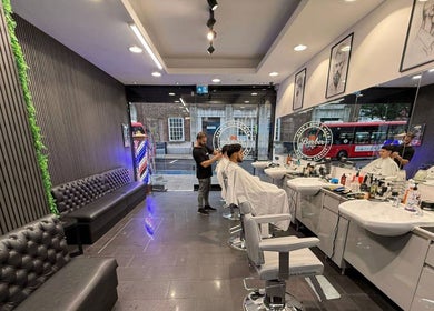 Modern interior of Db Barbers Tooting Bec, London, England, GB with customers receiving haircuts.