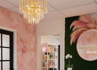 Уютный интерьер студии Permanent Makeup by Kira в Остине, Техас, США с розовыми стенами и люстрой.