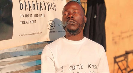 Person outside Favour Barbershop, Thembisa, Gauteng, ZA enjoying a moment, highlighting barber services.