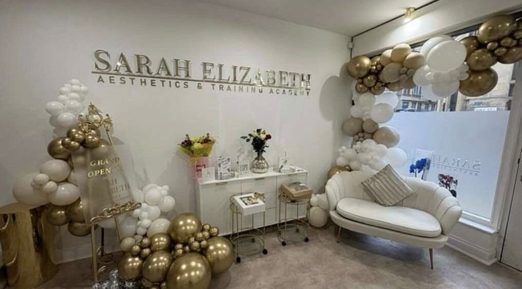 Chic reception area at Luxe Haven Cosmetics, Bradford, England, GB. Stylish decor with a cozy sofa and floral arrangements.