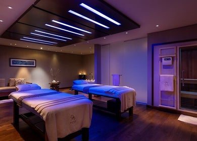 Elegant massage room at Zayna Spa, Abu Dhabi, AE, with soothing lighting and two cozy beds.