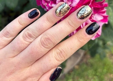 Elegant black and gold nail art by Nails by Becs in Desborough, England, set against a vibrant pink flower.