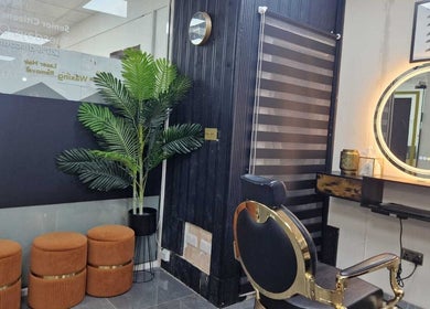 Elegant salon interior at Ray's House of Beauty, Hounslow, England, GB featuring stylish chairs and a lit mirror.