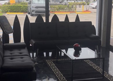 Elegant waiting area at Perfect Match Ink, Margate, Florida, US, with modern black couches and glass table.