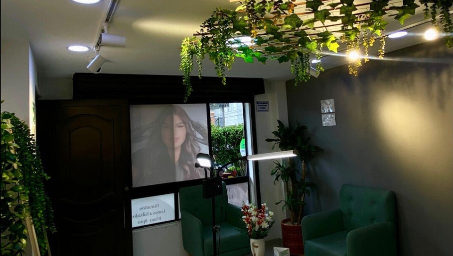 Interior acogedor de Elegance brows studio en Bello, Antioquia, CO, con decoración de plantas y sillones verdes.