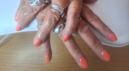 Polished and Pretty manicure with vibrant coral nails in Crynant, Wales, GB. Silver rings add elegance.