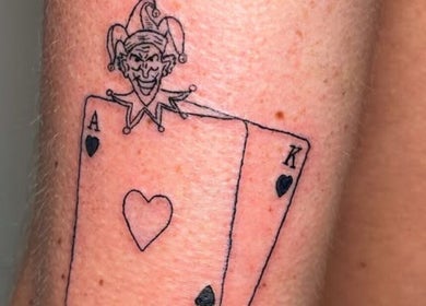 Unique joker and card tattoo at Nail and Needle Clinic, Great Warley, England, GB. Bold and artistic design.