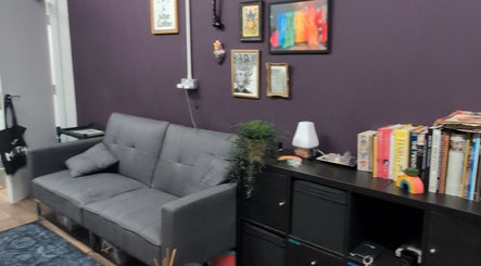 Cozy seating area at Shadow Bloom Studio, Oldham, England, GB with gray sofa and books on a shelf.