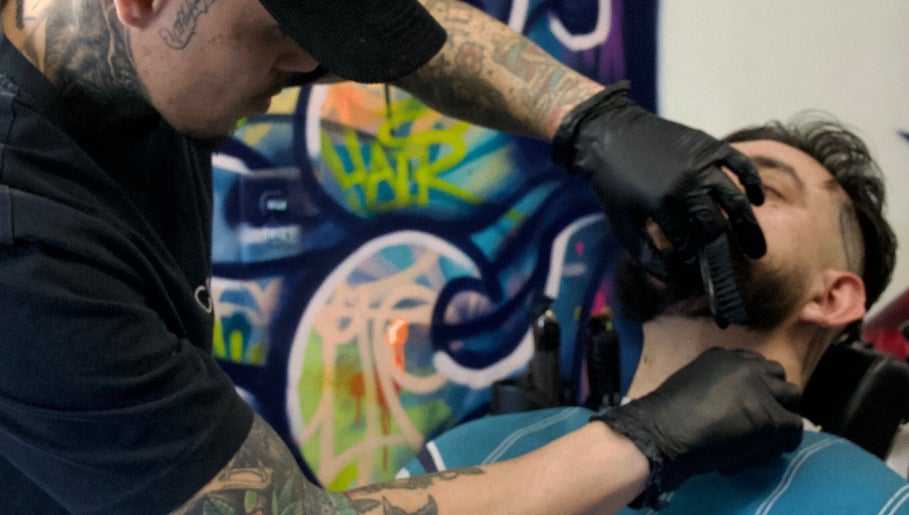 Expert providing a precise beard trim at Jonas Wayne, Norwalk, Connecticut, US, with colorful graffiti backdrop.