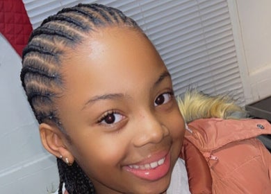 Young girl with intricate braids smiling at Soo Heavenly Braider LLC, US.