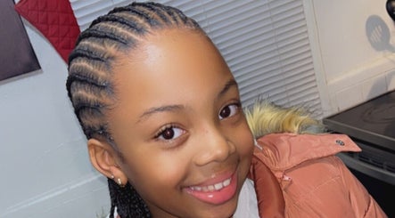 Young girl with intricate braids smiling at Soo Heavenly Braider LLC, US.