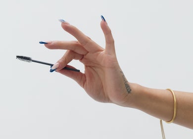 A hand with manicured nails holding a mascara wand at Mia Lashed, Brampton, Ontario, CA.
