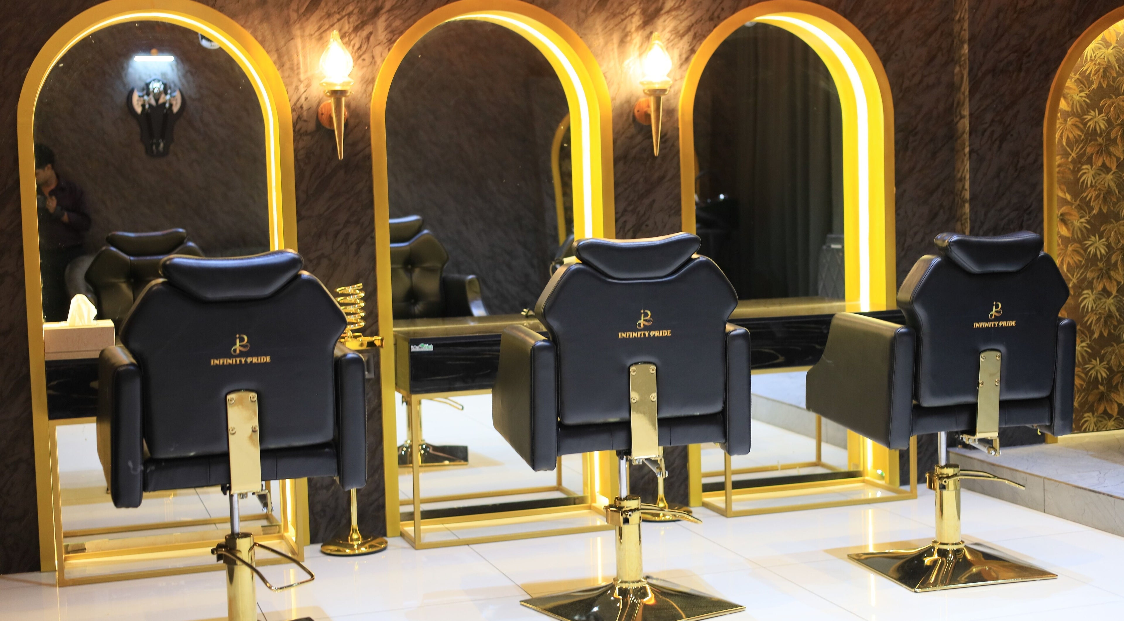 Luxurious salon chairs at Infinity Pride, Kottarakkara, Kerala, IN with elegant gold mirrors.