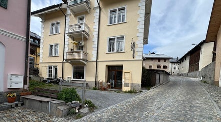 Die charmante Fassade von NUDE Atelier by Bianka in Scuol, Graubünden, CH, strahlt an einem sonnigen Tag.