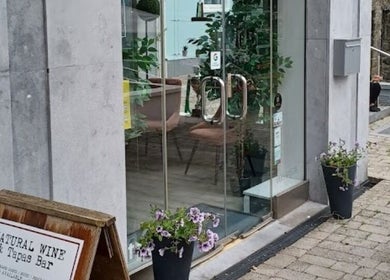 Front glass door entrance to Deeva Nails Westport, County Mayo, IE featuring plants and elegant decor.