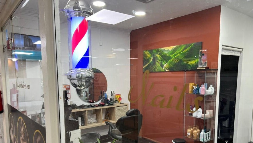Interior do Davidson Barbeiro em Carcavelos, Lisboa, PT com cadeira de barbeiro e produtos em exposição.
