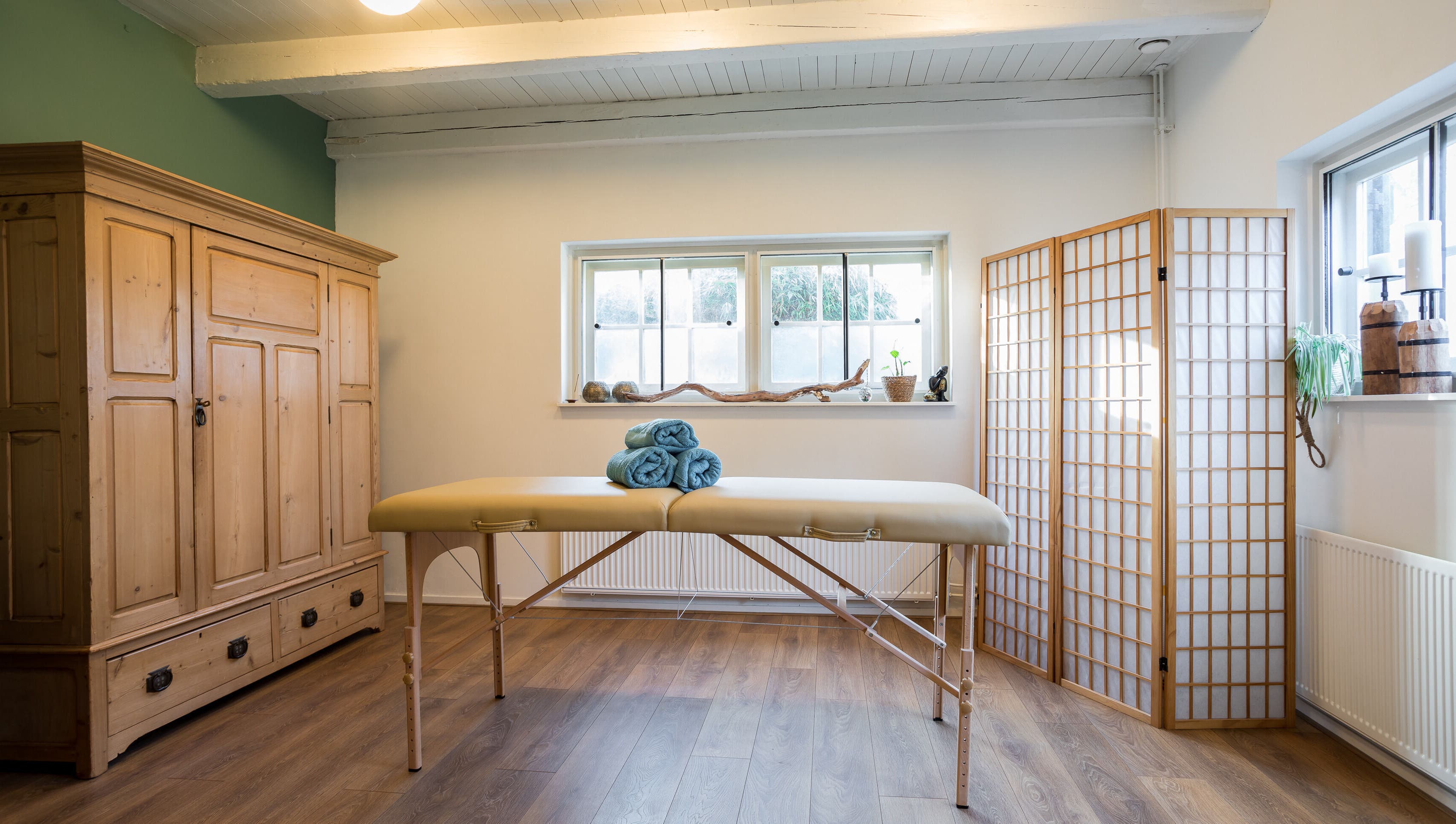 Rustige massageruimte bij Pauze met Marijke in Leiden, Zuid-Holland, NL met houten meubels en zachte verlichting.