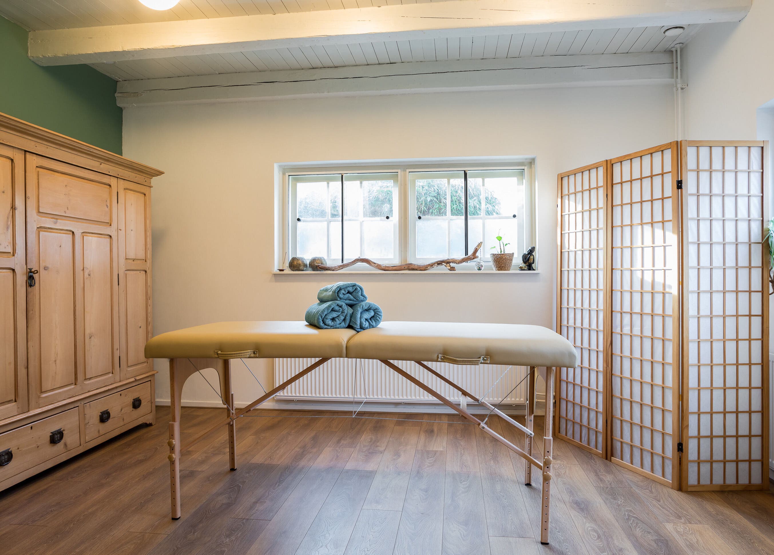 Rustige massageruimte bij Pauze met Marijke in Leiden, Zuid-Holland, NL met houten meubels en zachte verlichting.