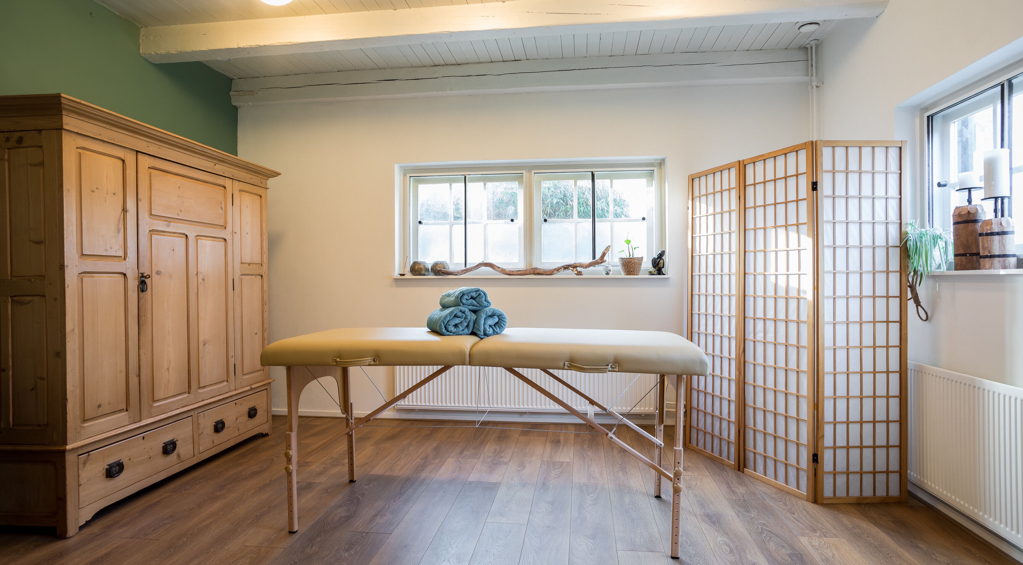 Rustige massageruimte bij Pauze met Marijke in Leiden, Zuid-Holland, NL met houten meubels en zachte verlichting.