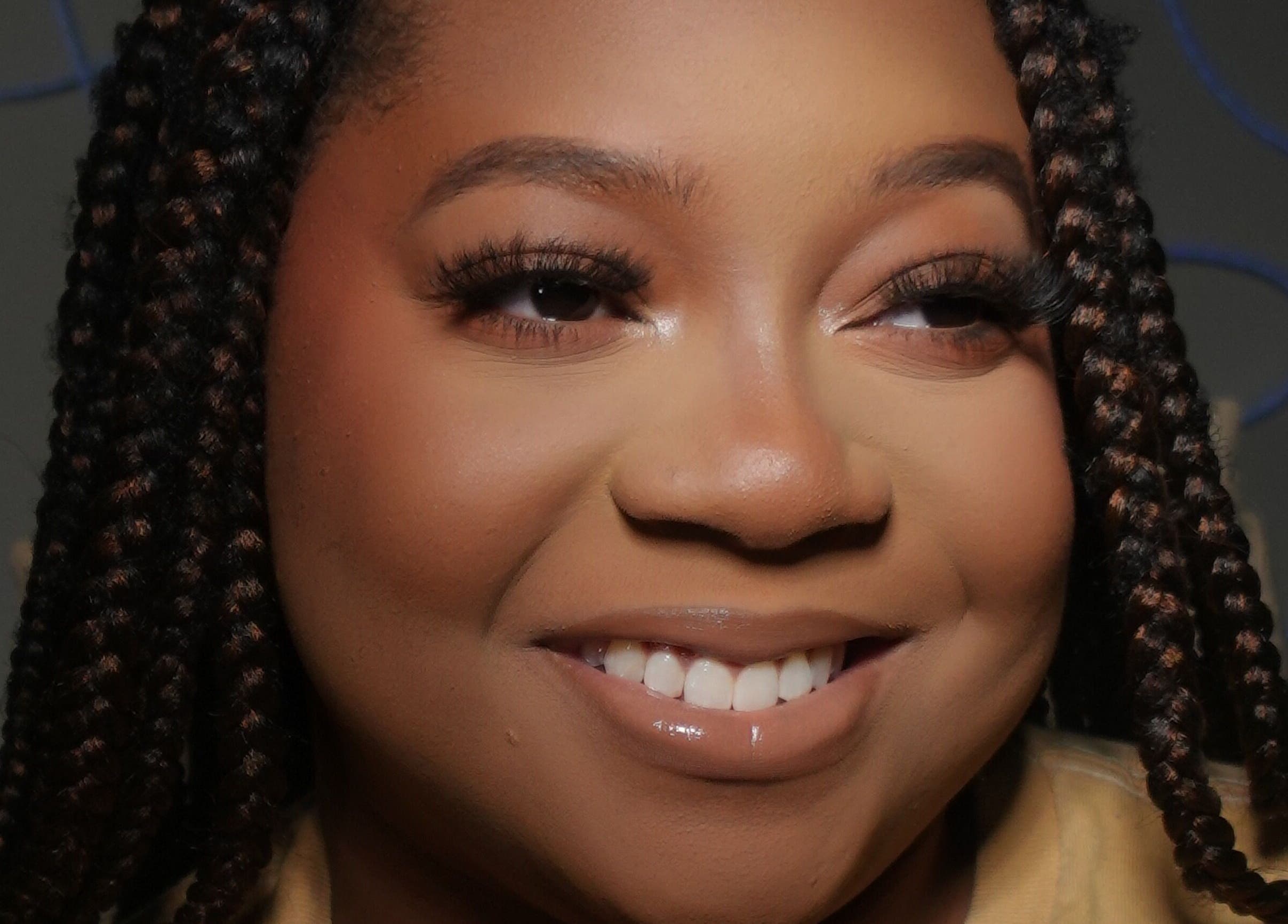 Woman with braided hair smiling at Luxe by Lia, Atlanta, Georgia, US.
