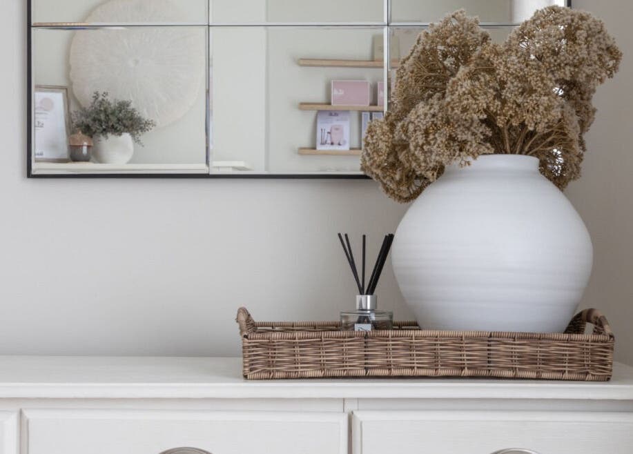 Elegant decor at Oak + Glow, Chaldon England, featuring stylish vase and mirror on a serene white dresser.