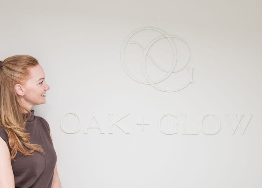 Person admiring the Oak + Glow logo on the wall in Chaldon, England, GB.