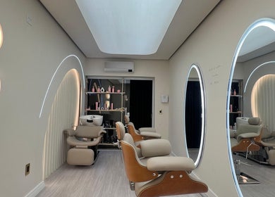 Interior sofisticado do salão Dor, São Paulo, BR, com espelhos iluminados e cadeiras de salão modernas.
