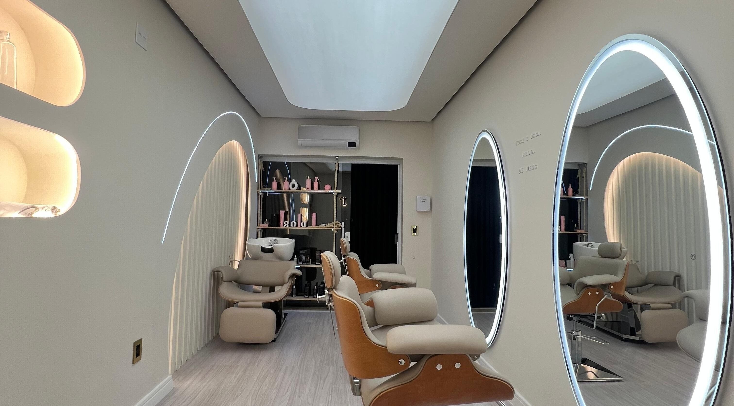 Interior sofisticado do salão Dor, São Paulo, BR, com espelhos iluminados e cadeiras de salão modernas.