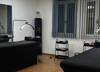 Sala de tratamiento en J.micropig, Ñuñoa, Región Metropolitana, CL, con camillas negras y lámparas modernas.