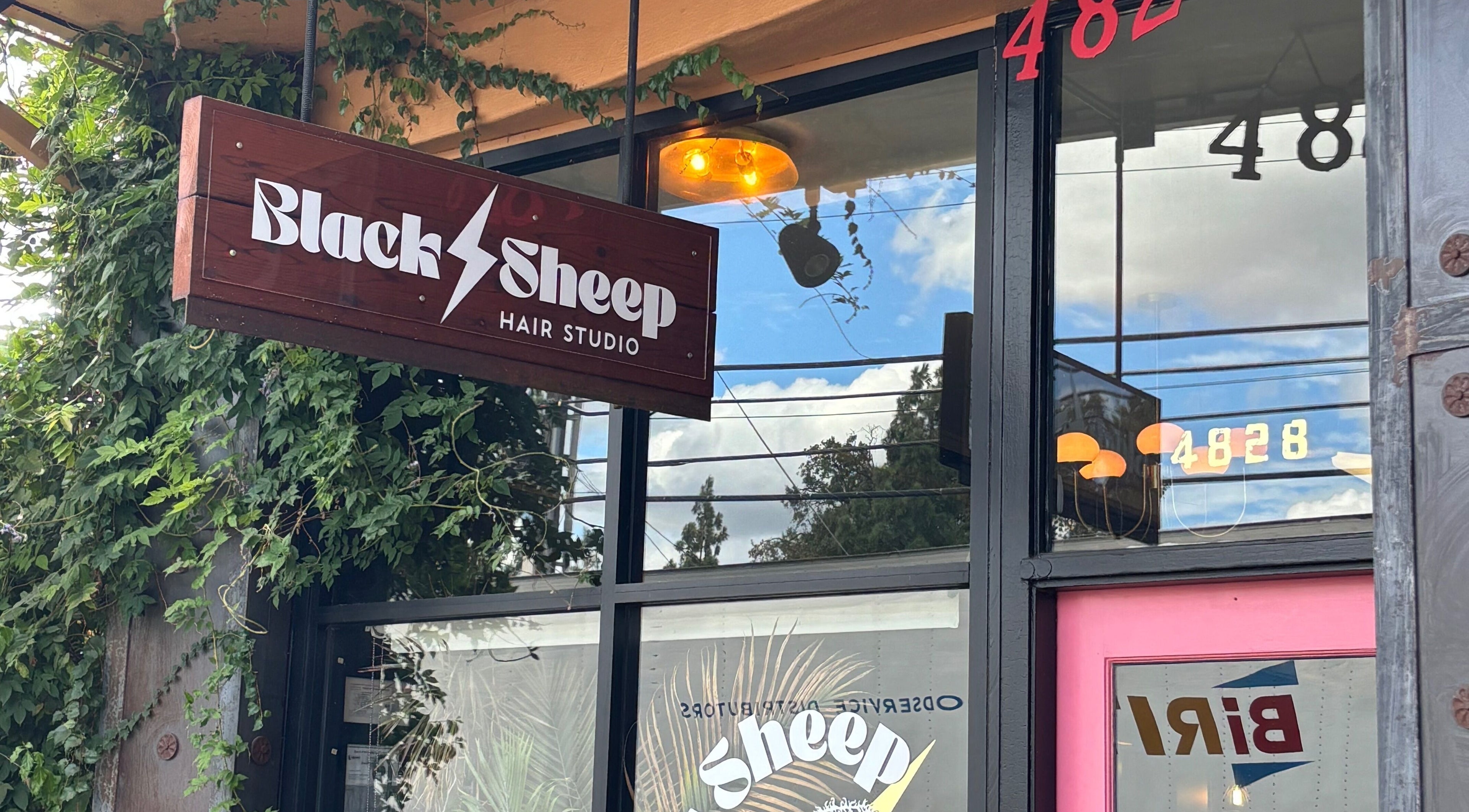 Entrance of Black Sheep Hair Studio LLC adorned with lush greenery in Sacramento, California, US.