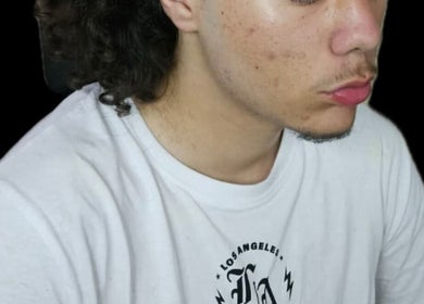 Young man with curly hair at a_taperz, London, England, GB wearing a white t-shirt.