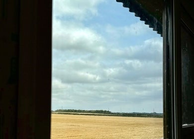 View from Calmia Treatments window showing fields in Stamford, England, GB under a cloudy sky.